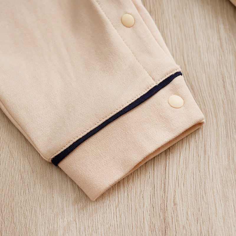 Elegant Gentleman Style Baby Outfit - Beige Cotton Jumpsuit with Checkered Collar cuff and snap button detail close-up on wooden surface
