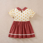 A cream and maroon polka dot toddler dress with a collar and white stripes.