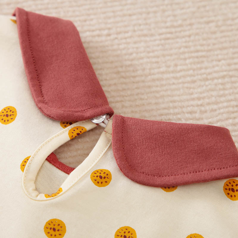 Close-up of a cream polka dot toddler dress with a reddish-brown collar.