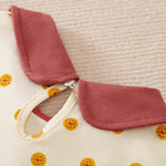 Close-up of a cream polka dot toddler dress with a reddish-brown collar.
