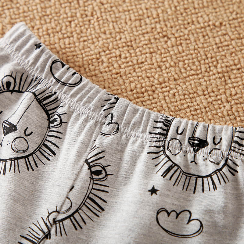 Children's shorts with black sun and cloud patterns on a beige carpet background