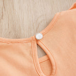 Baby Butterfly Dress Long Sleeve | Hushies Boutique showing close-up of pearl button closure on soft peach fabric infant clothing