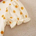 Close-up of a cream sleeve with yellow cookie patterns and ruffled cuff.