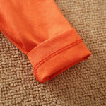 Close-up of an orange fabric sleeve on a textured brown surface