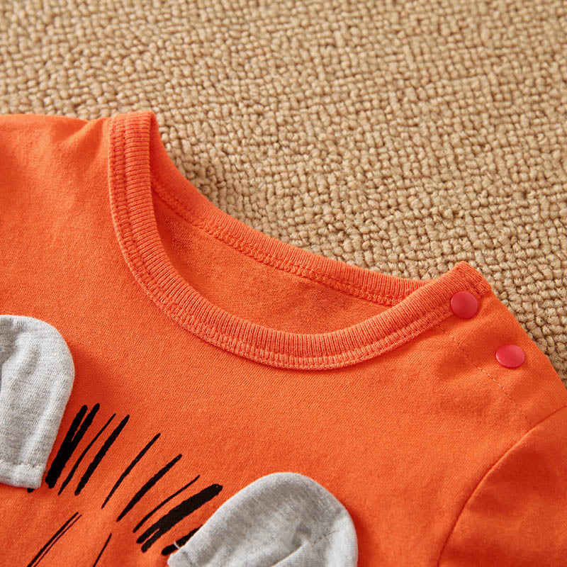 Close-up of an orange children's outfit with gray ears and black design on a beige carpet background.