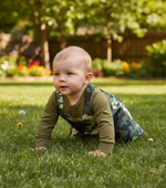 Crawling baby boy wearing a camouflage print jumpsuit, exploring the outdoors in stylish camouflage baby clothes.