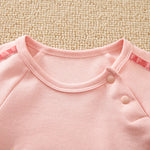 Unicorn Baby Jumpsuit Pink Romper | Hushies Soft Bow close-up of neckline and snap button closure on soft pink fabric