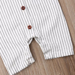 Close-up of a white and grey striped baby jumpsuit with brown and white buttons.