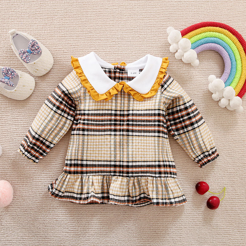 Plaid dress shirt with ruffled collar on a textured surface with shoes and decorative items.