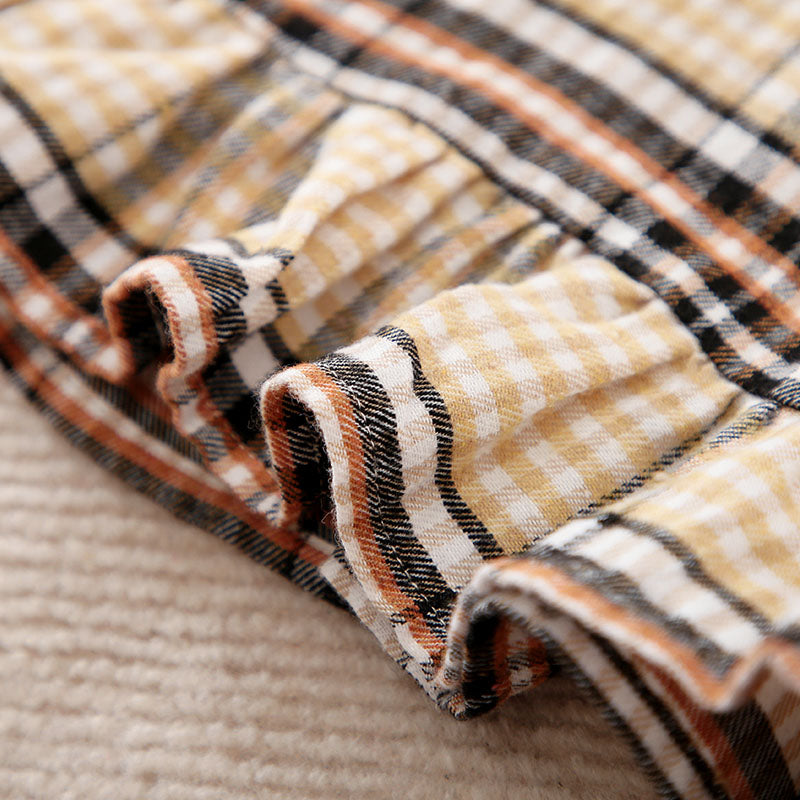 Close-up of plaid fabric with brown, black, and beige colors on a textured surface.