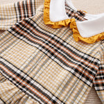 Plaid dress shirt with yellow ruffled trim on a neutral background