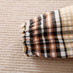 Plaid patterned sleeve on a textured beige background