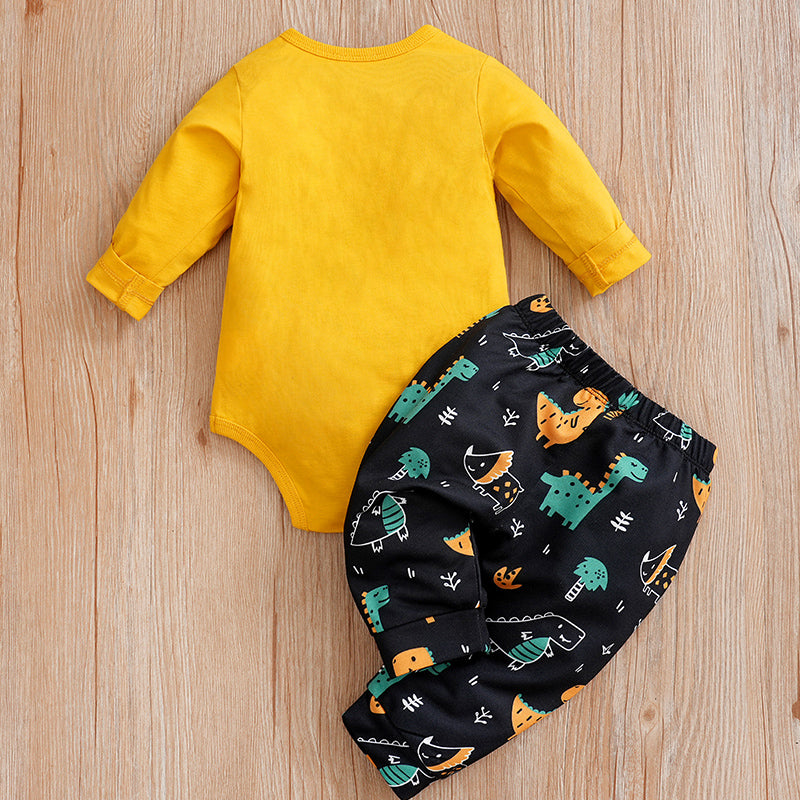 Yellow baby onesie and black patterned pants on a wooden surface