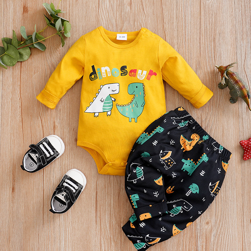 Yellow baby bodysuit with dinosaur design, black pants with dinosaur pattern, and black shoes on a wooden surface.