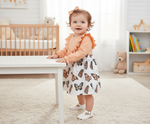 Happy baby in an Adorable Baby Butterfly Dress with long sleeves, standing and smiling, designed with a charming butterfly print for special moments.
