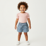 A happy child wearing cute kids clothing, showcasing a playful poke dot sleeve top paired with fashionable denim shorts, standing confidently in a bright white background.