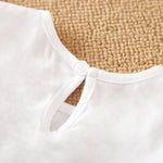 Button on back of baby romper on a textured beige surface