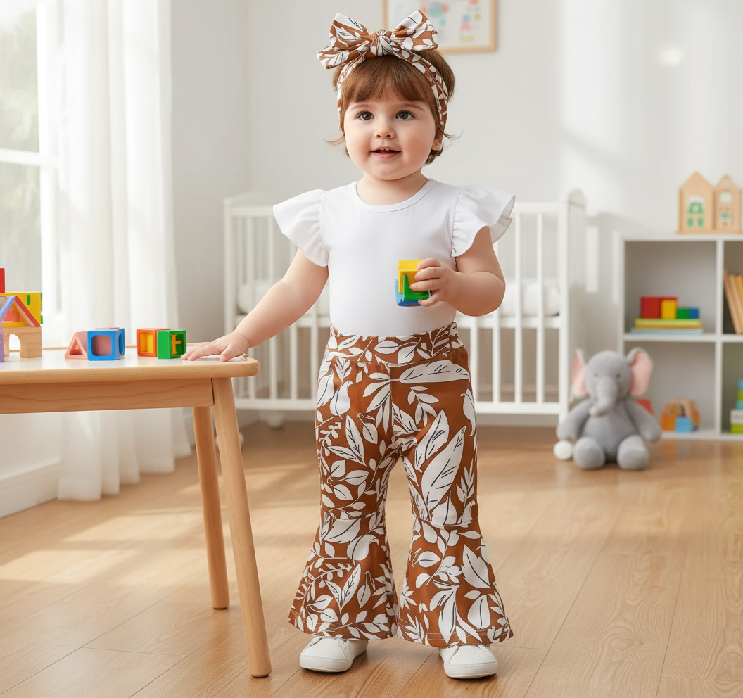 Trendy Baby Girl Outfits: 3-Piece Bell-Bottom Pants Set with White Bodysuit & Headwrap. Cute toddler wearing a stylish floral bell-bottom outfit, holding a toy in a bright playroom.