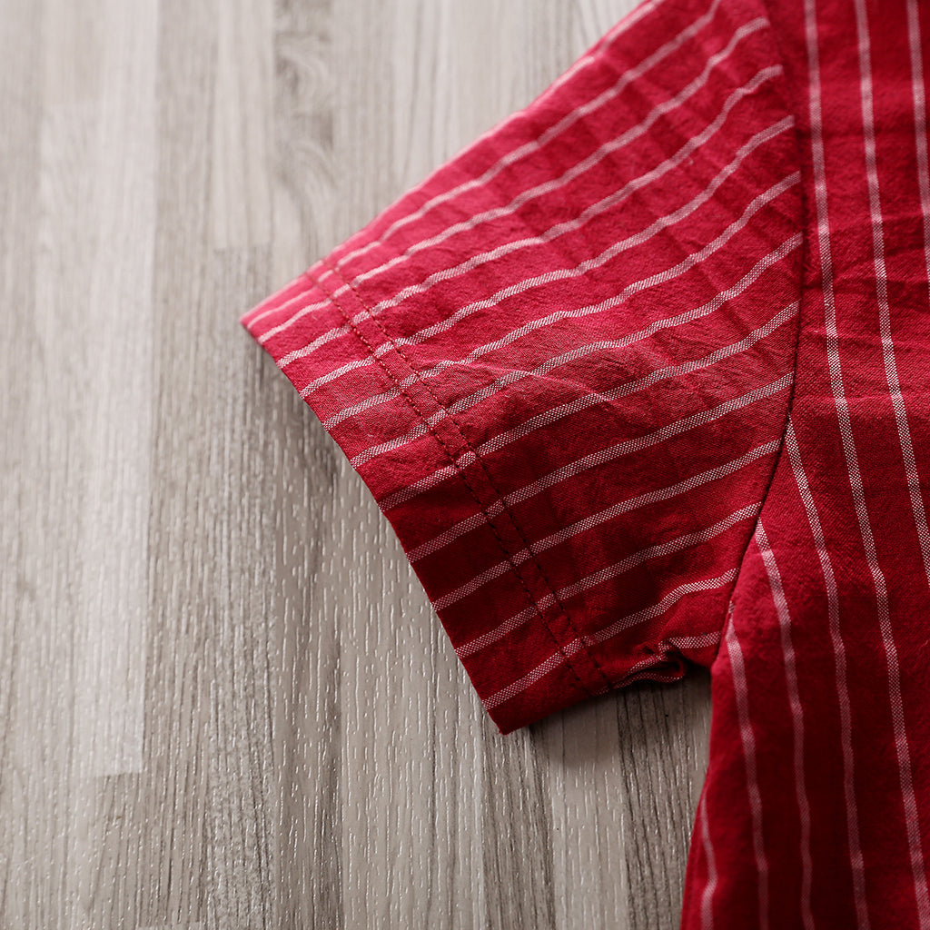 A close-up of the short sleeve of the Adorable 1-Piece Striped Infant Clothing Jumpsuit With Bow Tie & Button-Up Front, featuring red fabric with thin white vertical stripes, laid flat on a light wood surface.