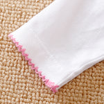 Close-up of a white cotton sleeve with a decorative pink scalloped edge.