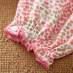 Baby romper with heart pattern on bottom half of romper on a textured surface