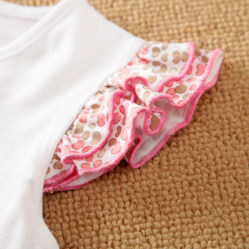 White garment with pink and brown patterned trim on sleeve on a textured surface