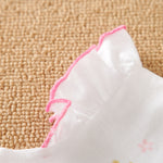 White fabric with pink trim on sleeve of baby romper on a textured beige surface