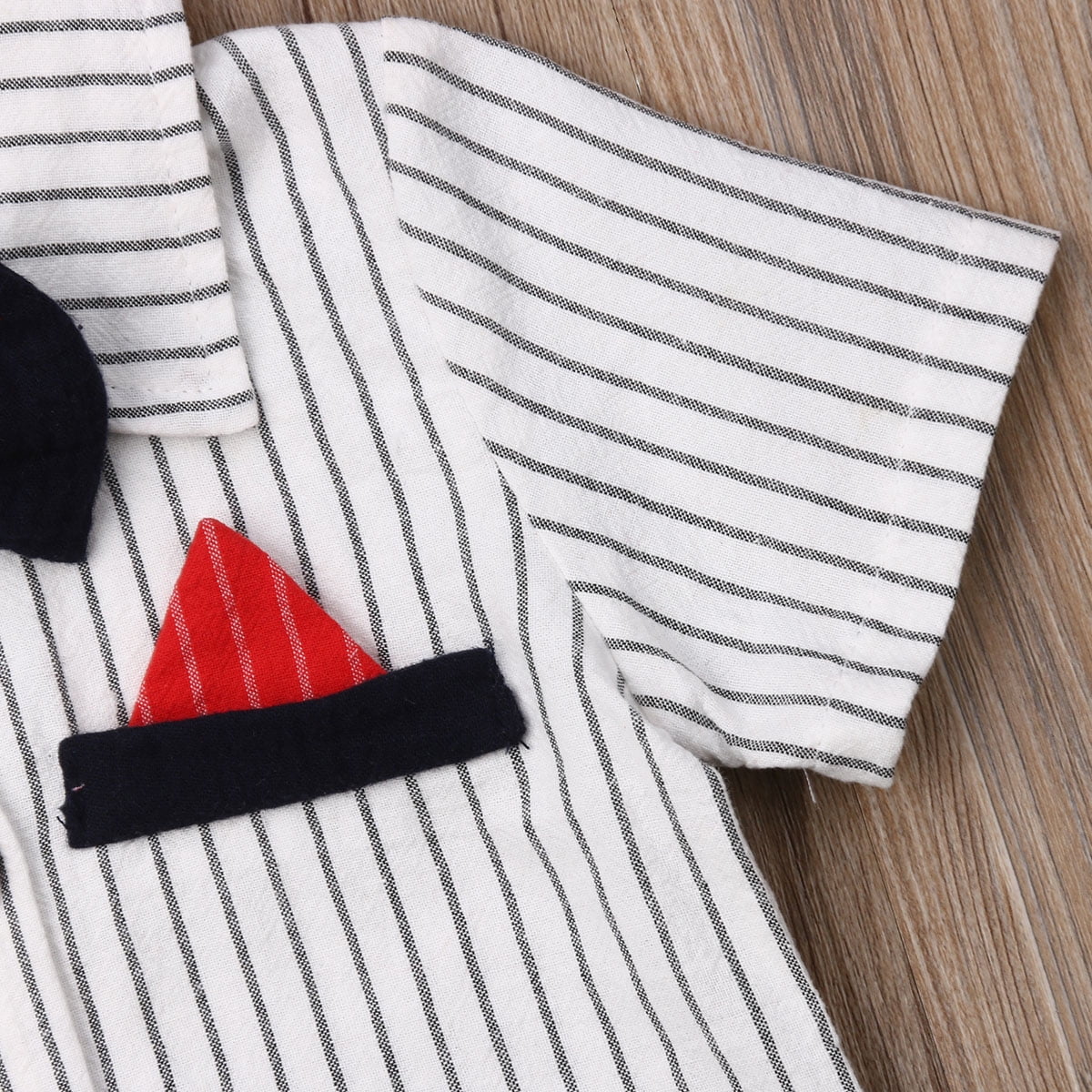 Striped baby jumpsuit with black bow tie and red pocket square.