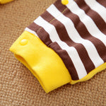 Close-up of a brown and white striped cotton garment with a yellow cuff and snap.