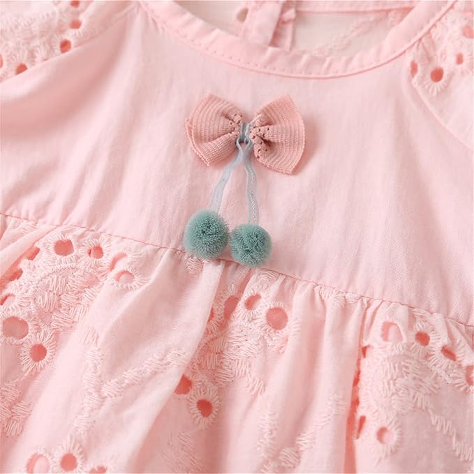 Light pink cotton baby dress featuring a bow, teal pom-poms, and eyelet lace.