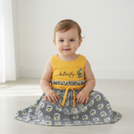 Adorable toddler wearing a butterfly dress for girls, featuring a bright yellow top and twirling floral skirt, perfect for playtime.