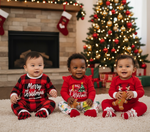 Three adorable babies in festive outfits, including a Gender Neutral Baby Jumpsuit, sharing holiday cheer around a decorated Christmas tree.