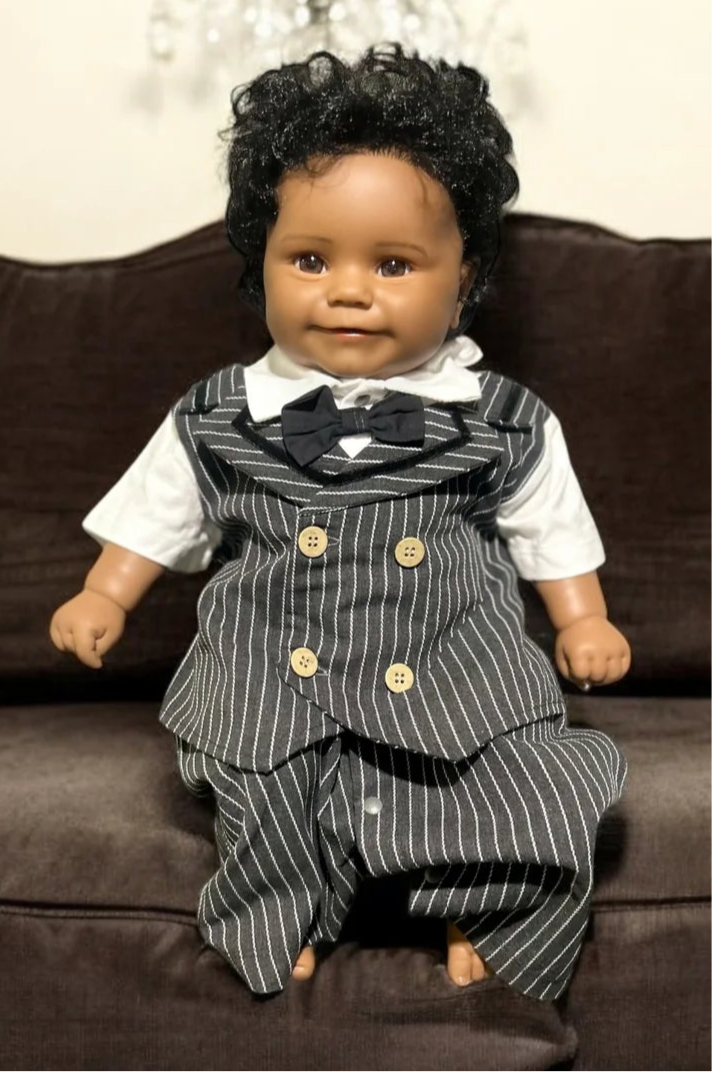 A charming black baby doll dressed in a pinstripe suit and bow tie, embodying the essence of a little gentleman.