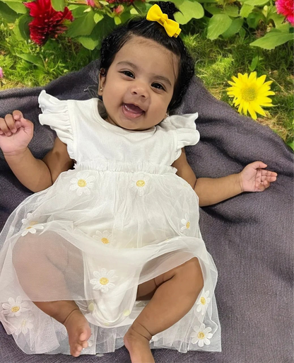 Precious baby girl in a lovely white dress, comfortably nestled on a blanket, embodying pure cuteness and tranquility.