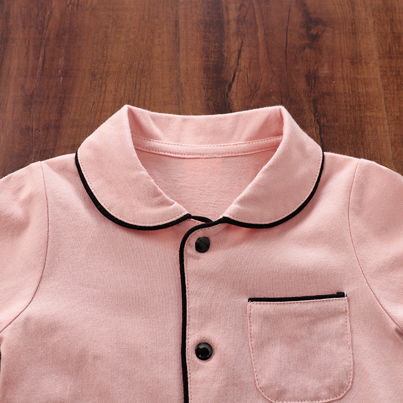 Close-up of a pink pajamas with black trim on a wooden surface