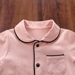 Close-up of a pink pajamas with black trim on a wooden surface