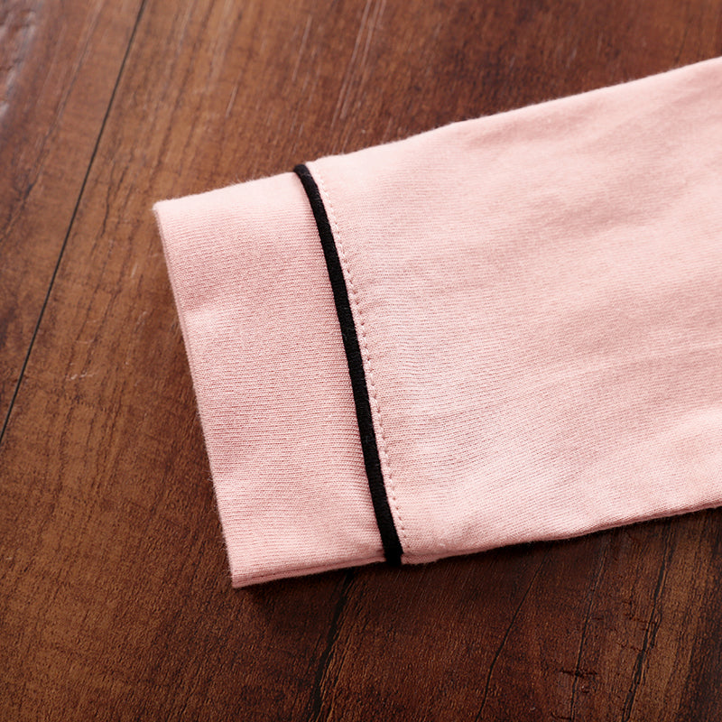 Folded pink fabric with a black edge on a wooden surface