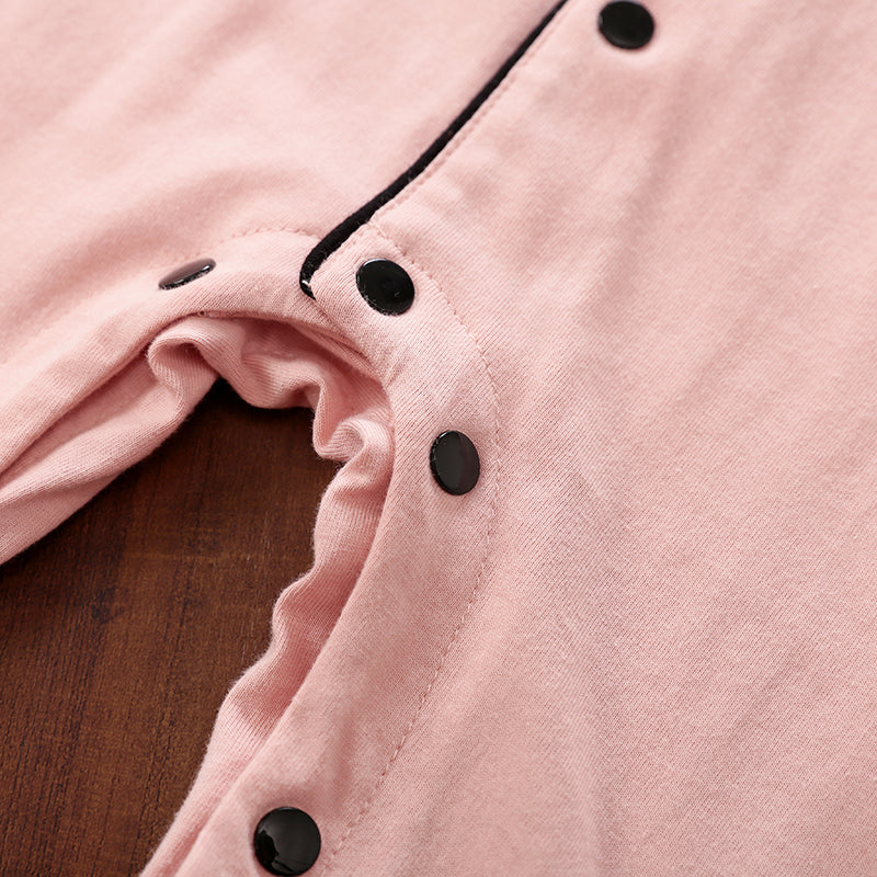 Close-up of a pink garment with black snap buttons on a wooden surface