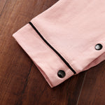 Close-up of a pink fabric with black snap buttons on a wooden surface
