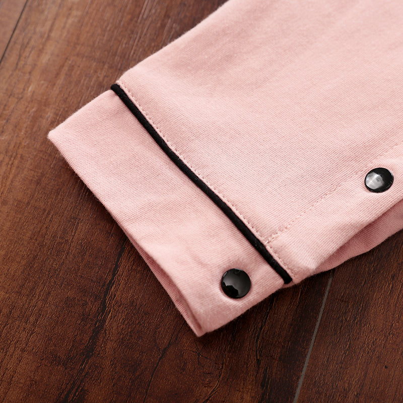 Close-up of a pink fabric with black snap buttons on a wooden surface