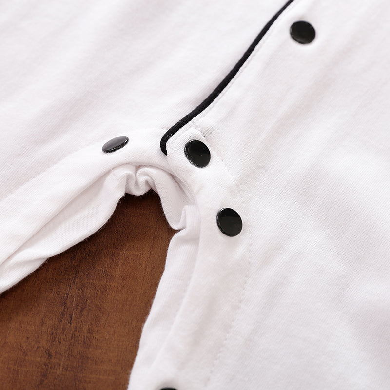 Close-up of a white garment with black snap buttons on a brown surface