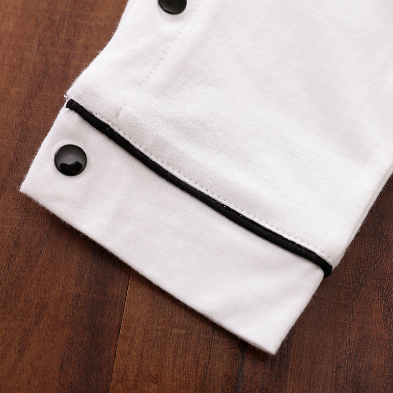 White fabric with black trim and snap buttons on a wooden surface