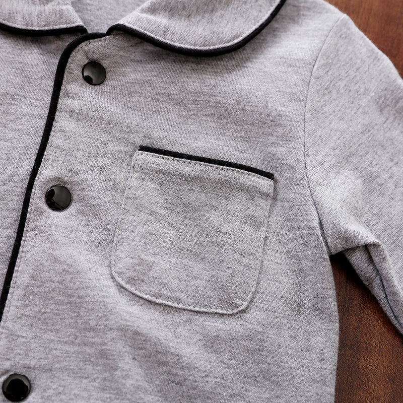 Close-up of a gray baby pajamas with black snap buttons and trim on a wooden surface