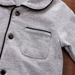 Close-up of a gray baby pajamas with black snap buttons and trim on a wooden surface